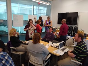 Participants are grouped around a table, discussing and recording their ideas.